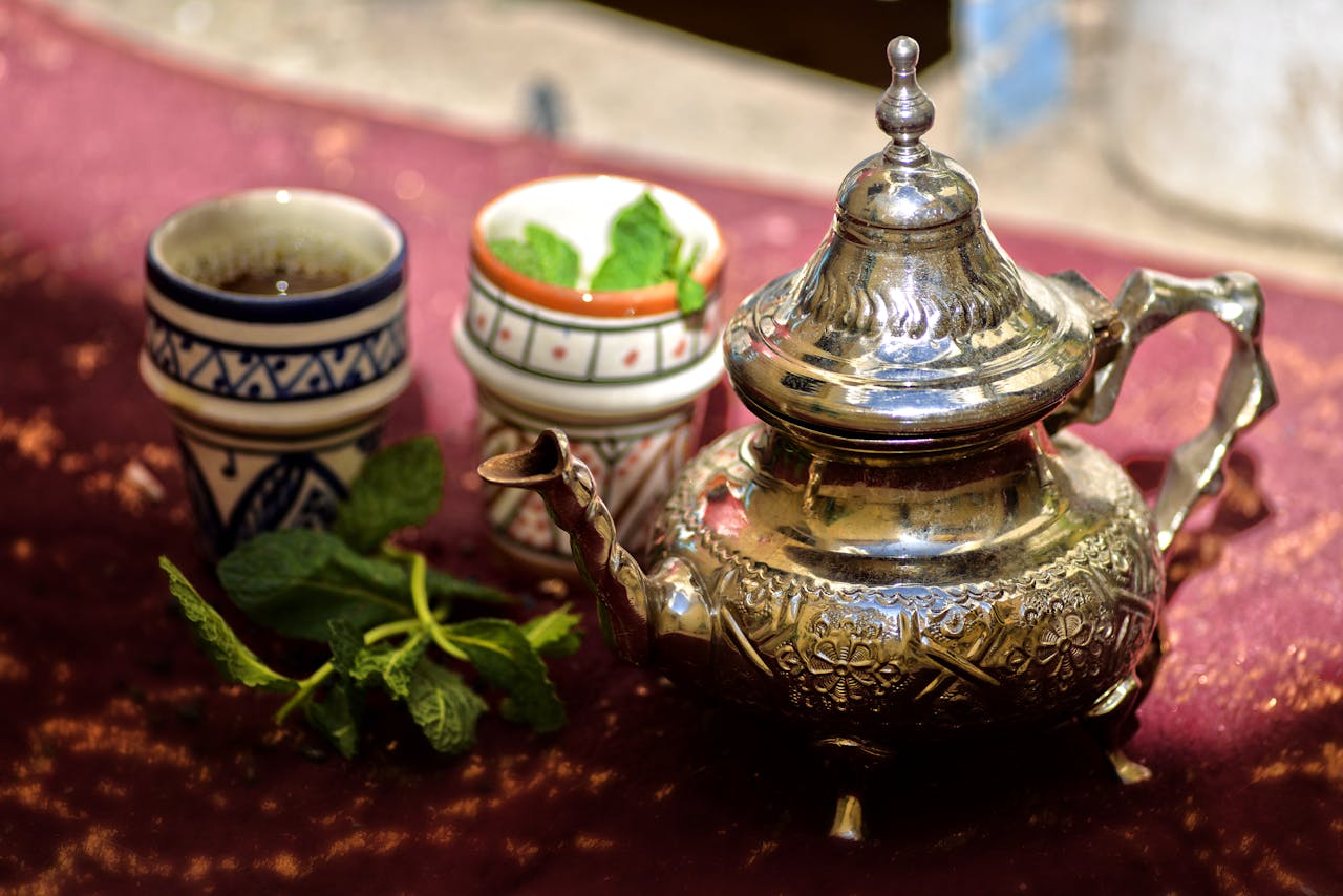 A traditional Moroccan mint tea set with a silver teapot and cups outdoors in Fès, Morocco.