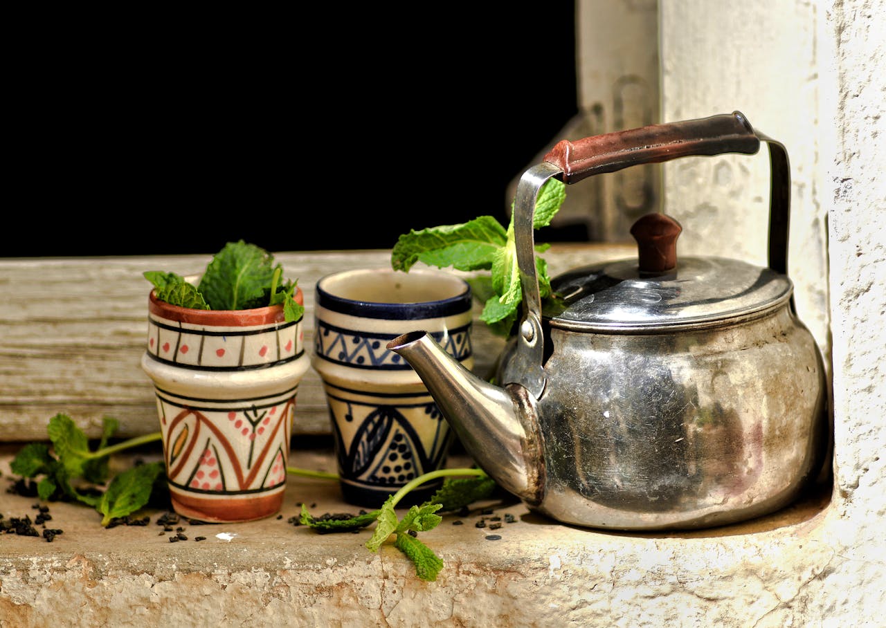 Authentic Moroccan tea scene featuring a teapot and traditional cups with fresh mint leaves.