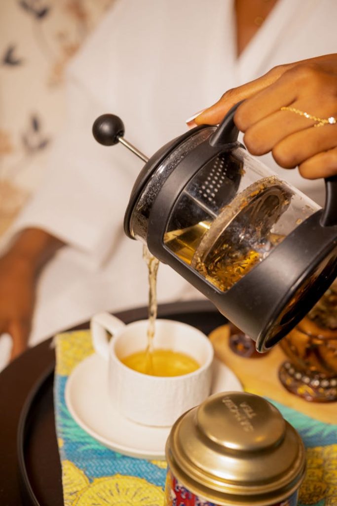 Close-up of pouring tea from a French press into a cup, capturing a cozy morning moment.